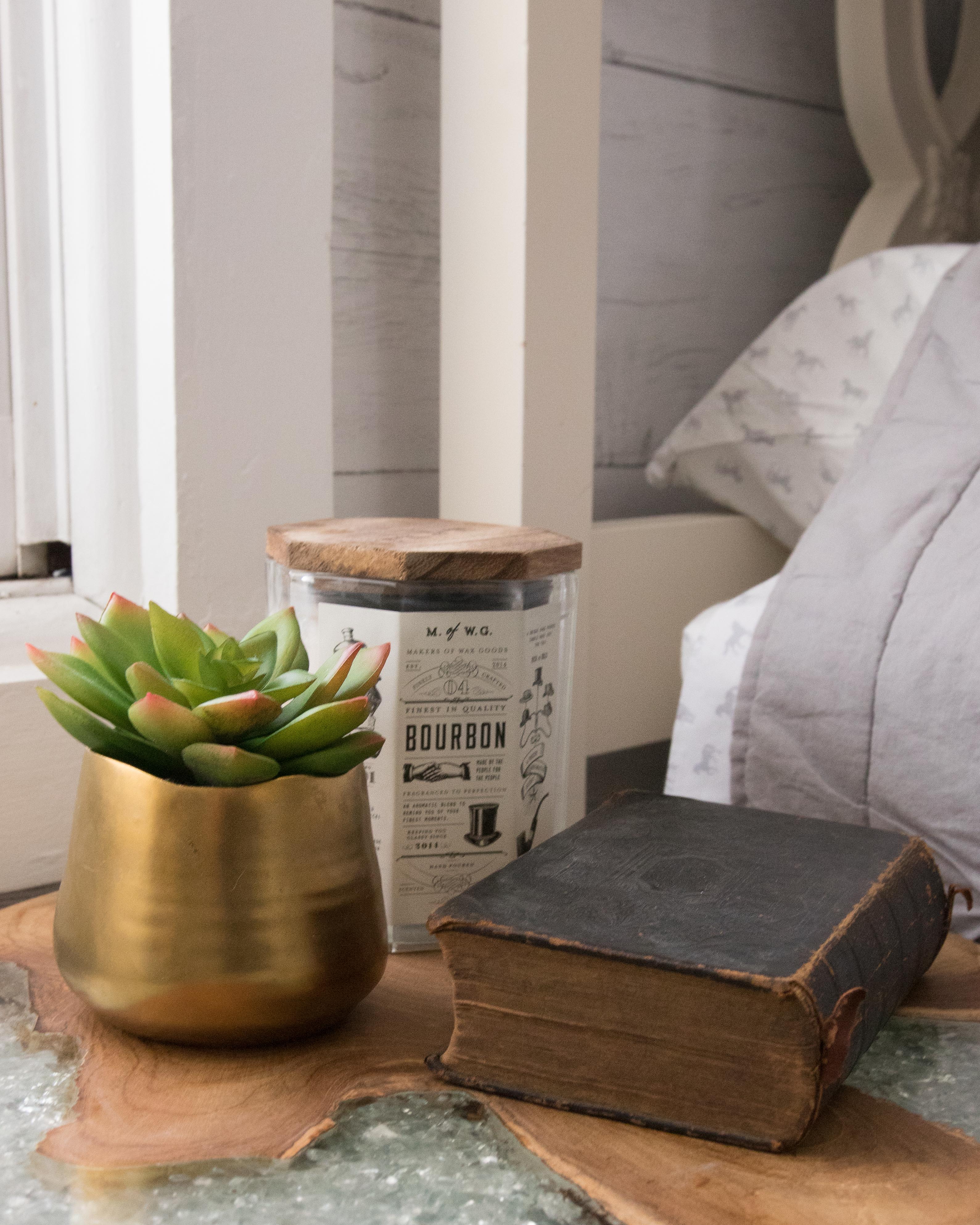 vintage book, bourbon candle, and succulent on a crystal side table