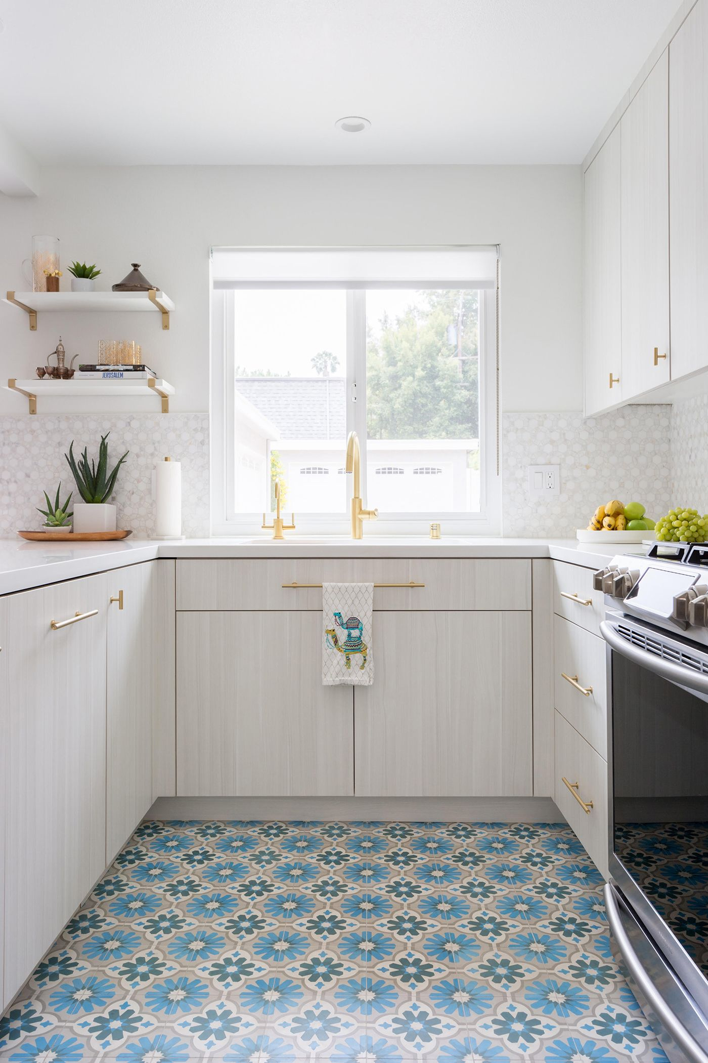 All white kitchen with gold hardware and blue and tan Moroccan inspired tile floor
