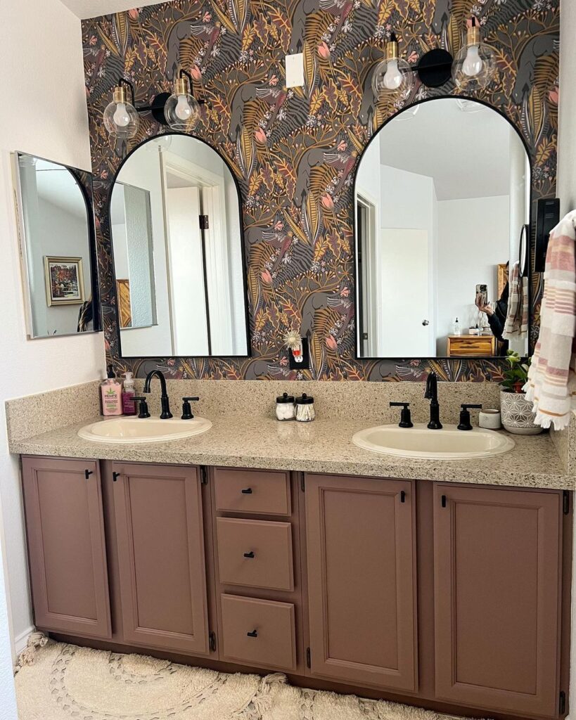 Cranberry and gold peel and stick NuWallpaper makes this powder room with gold accents and deep mauve paint colorings feel cozy and homey. 
